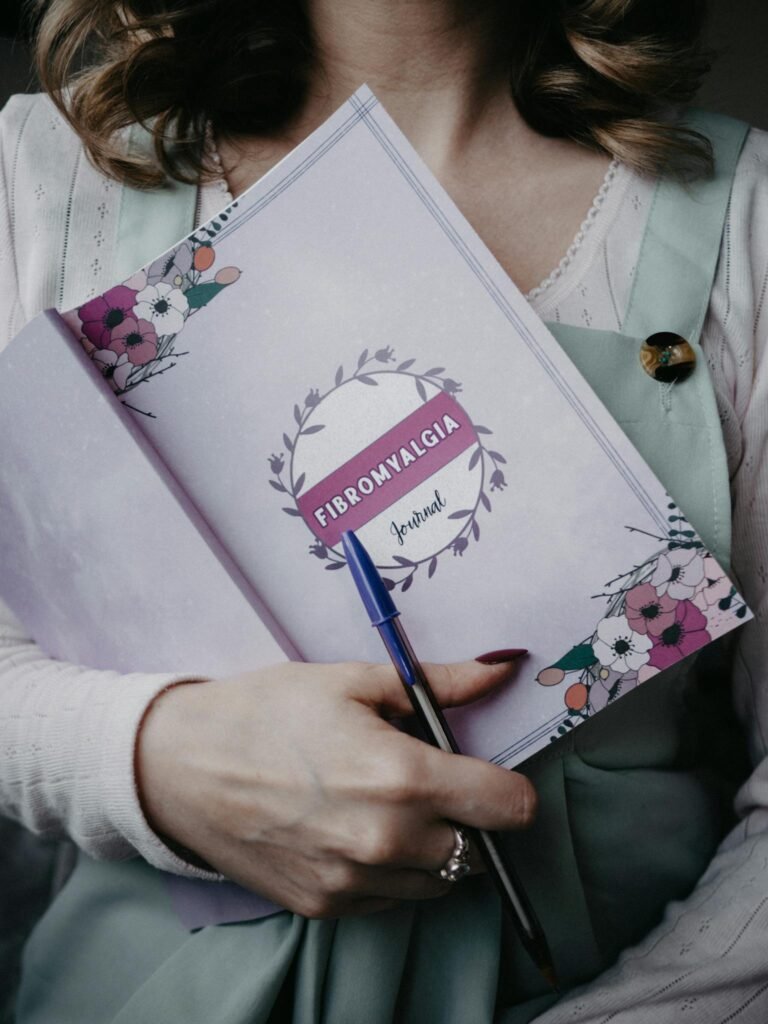 A woman holding a fibromyalgia journal with floral design, emphasizing health and awareness.